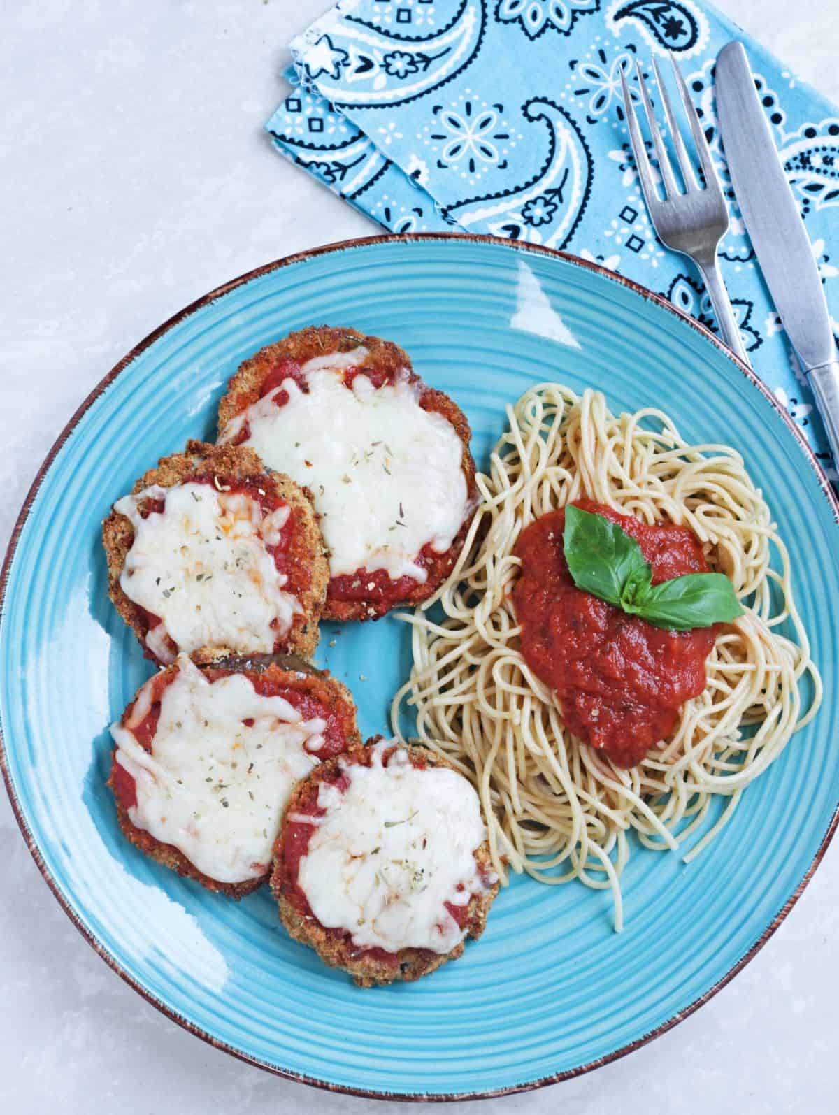 Eggplant parmesan with pasta and sauce in a blue plate