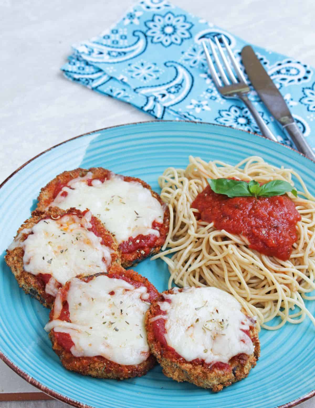Eggplant parmesan with melted cheese and spaghetti on a plate